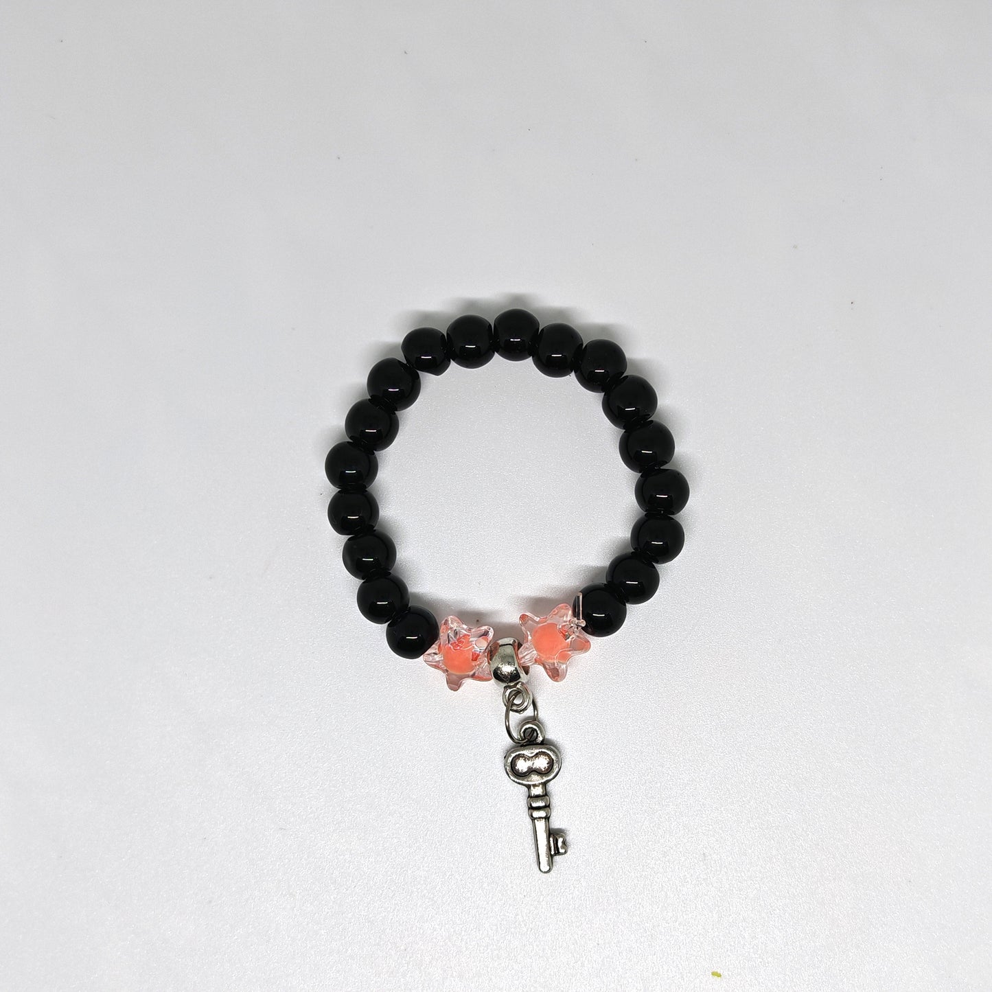 Black beaded bracelet with butterfly and key charm on a white background