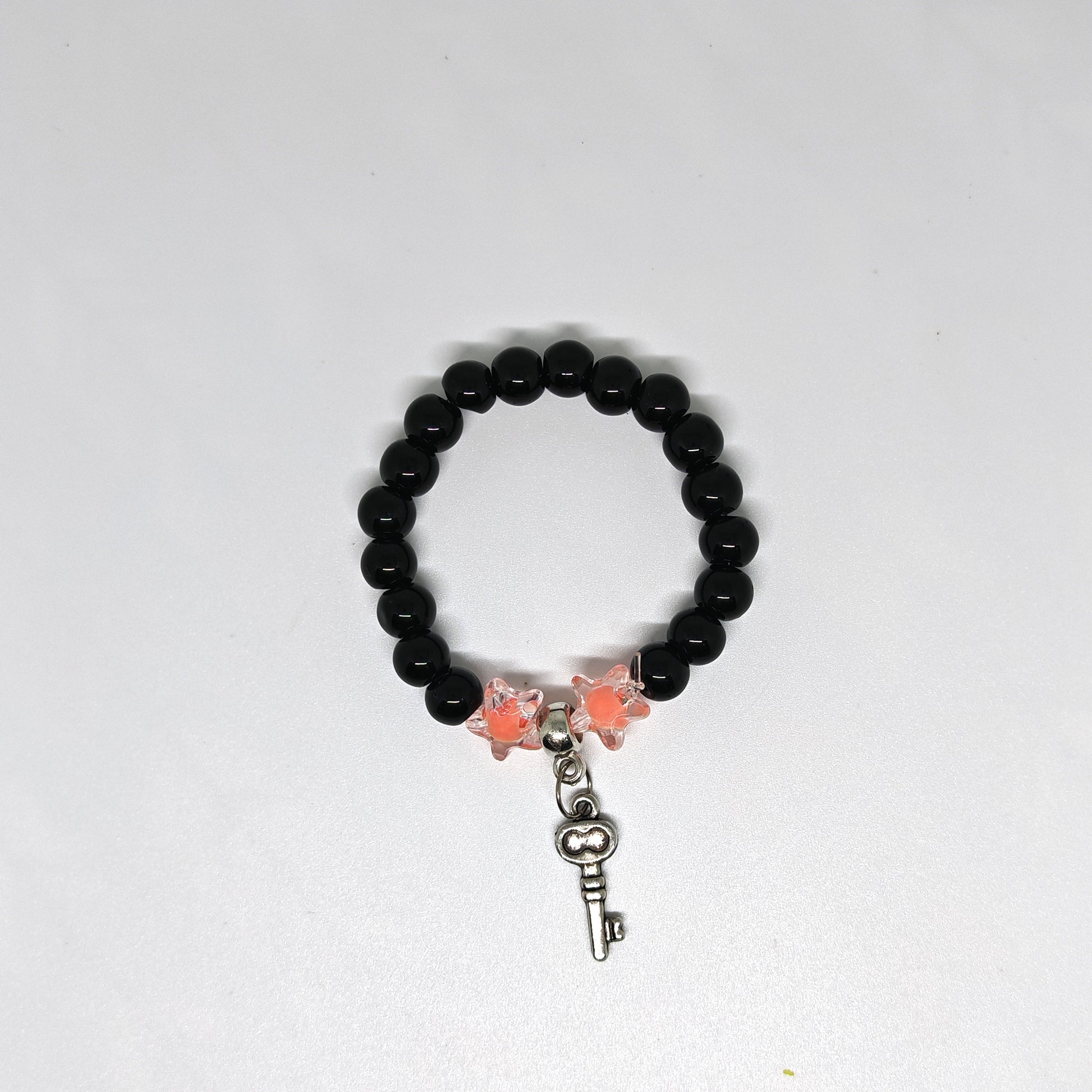 Black beaded bracelet with butterfly and key charm on a white background