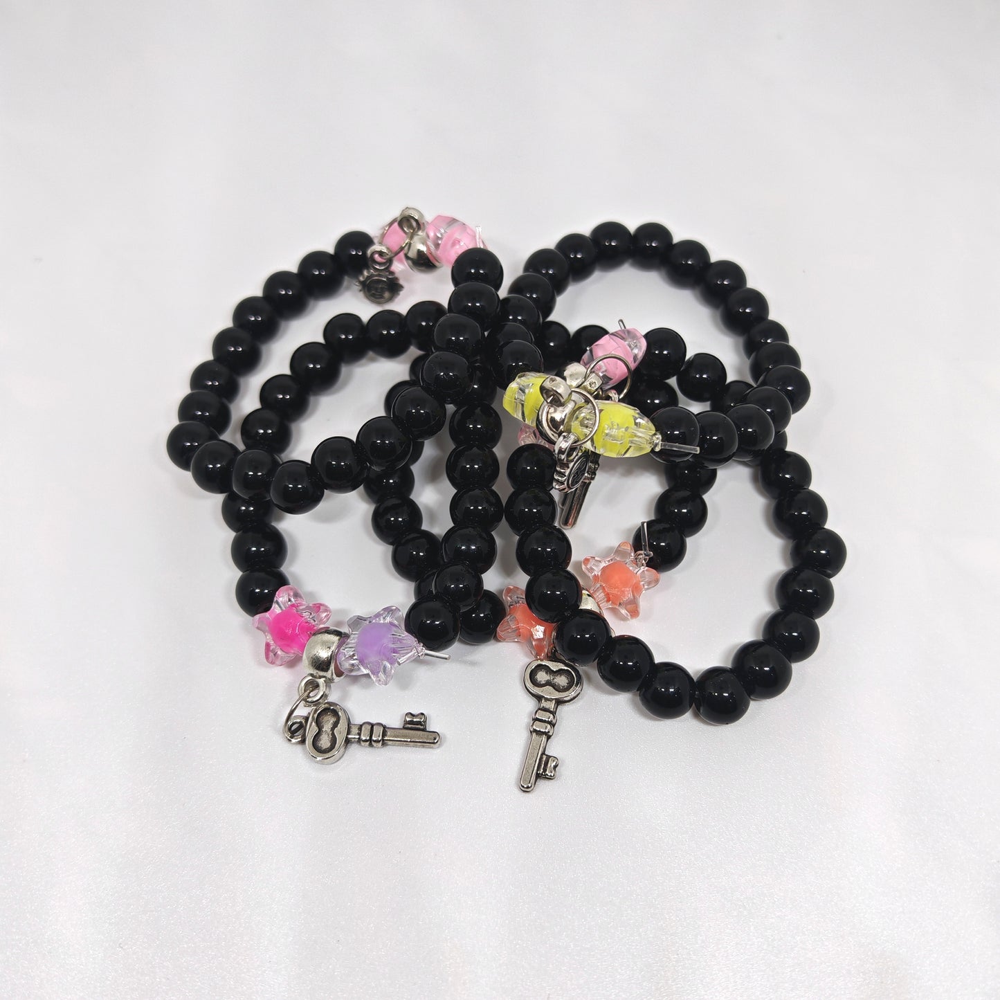 Black beaded bracelets with various charms on a white background
