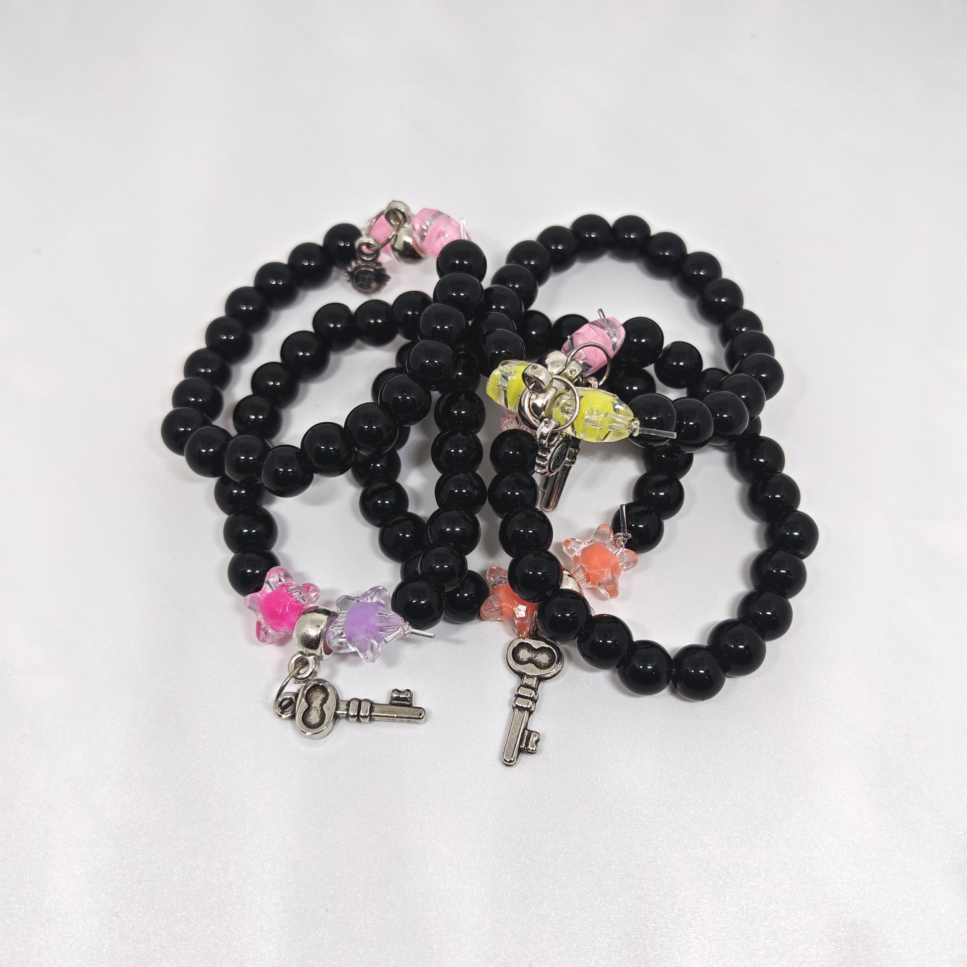 Black beaded bracelets with various charms on a white background