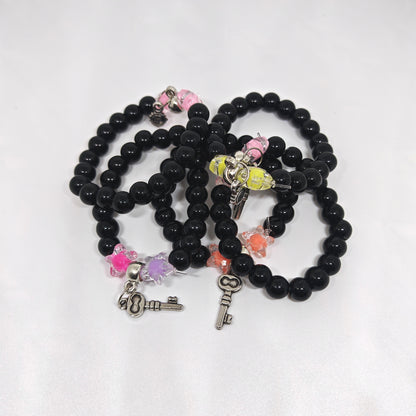 Black beaded bracelets with various charms on a white background