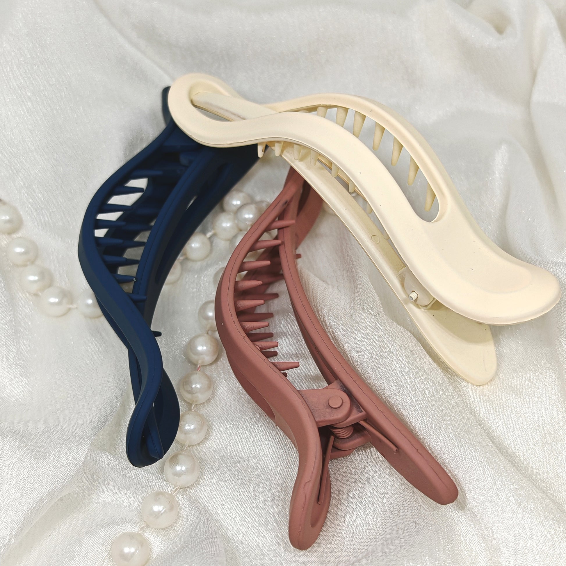 Three banana hair clips in blue, beige, and pink 