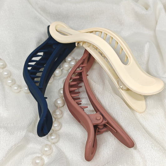 Three banana hair clips in blue, beige, and pink 